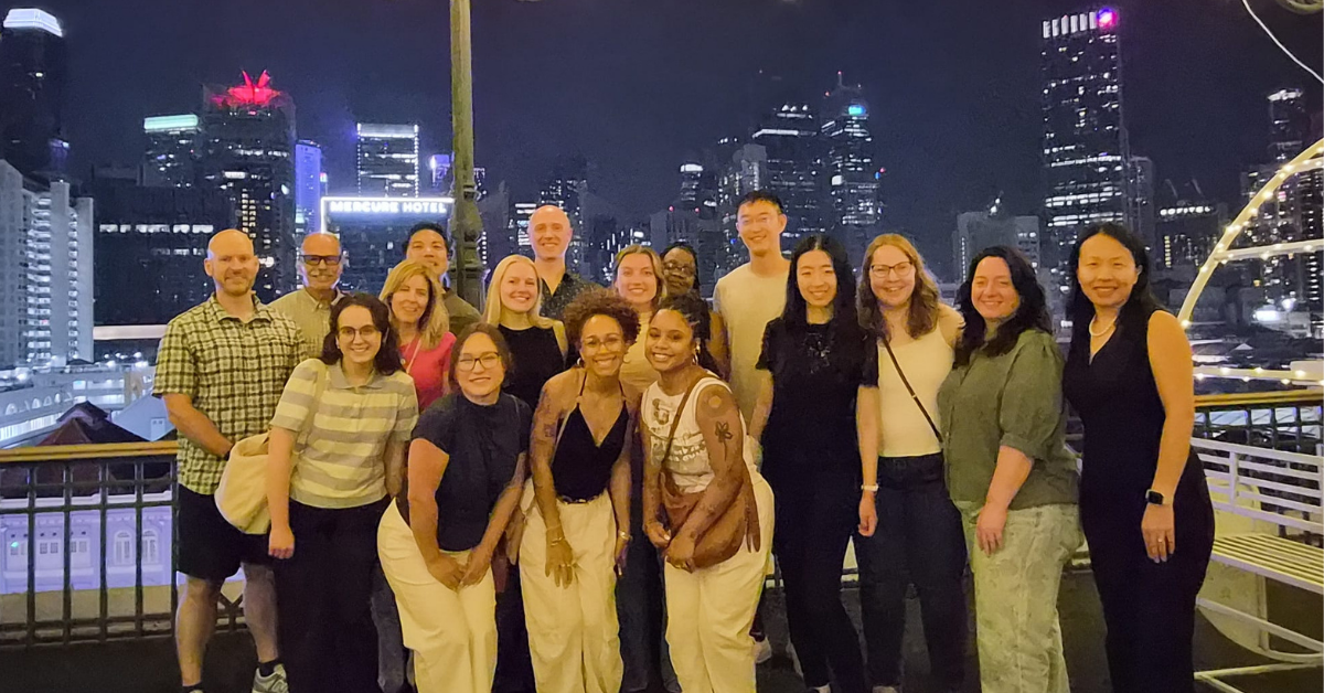 Group of people standing in front of a window with the Singapore skyline behind them